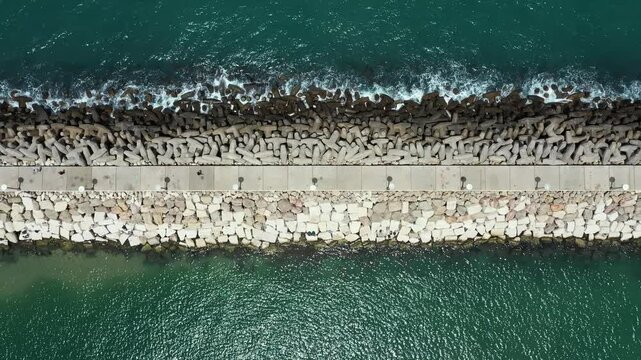 Aerial video of a man running on the breakwater of Ashkelon Israel