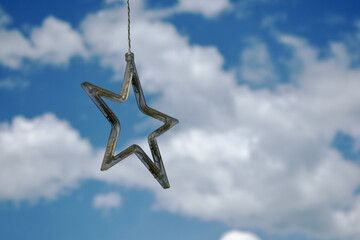 Hanging star ornament against a cloudy blue sky background