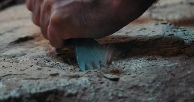 It is carved by hand, with a hammer and chisel, to match the patterns on the stone. Dust flying from the stone and chisel detail.