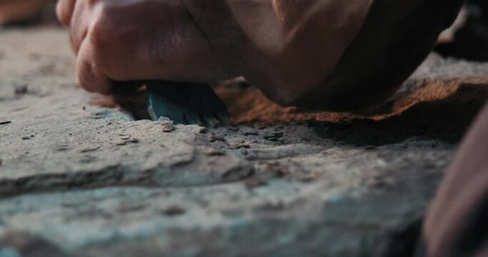 It is carved by hand, with a hammer and chisel, to match the patterns on the stone. Dust flying from the stone and chisel detail.