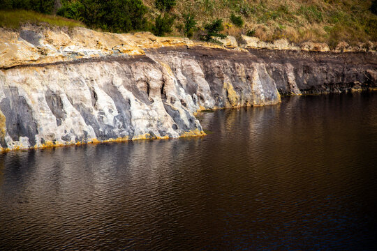 View of the jagged rock face with mineral residues at the edge of the lake, Solfatara locality, Pomezia, Rome, Italy