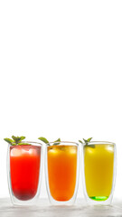 three glass glasses with a double bottom with lemonade in red, orange and yellow, decorated with a sprig of mint. Summer refreshing drinks. White background.
