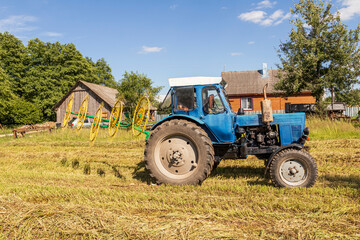 Obraz premium natural lighting. The driver of a blue tractor cleans hay and oats. close-up