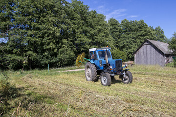 natural lighting. The driver of a blue tractor cleans hay and oats. close-up
