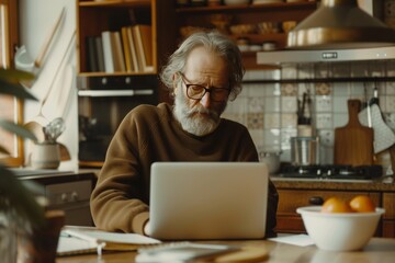 Senior remote worker in glasses typing report on laptop at kitchen table, home office setting
