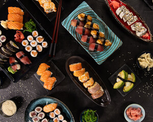 Top view of traditional japanese cuisine . Sushi rolls set with salmon , tuna fish and vegetable served on black stone table . Asian food on black stone slate with chopsticks .