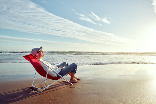 solo mature hispanic man lying on beach chair resting or relaxing with eyes closed on the beach shore	