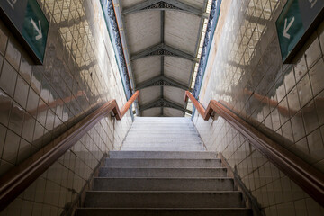 Stairs going up with railings and walls on the sides with two direction arrows.