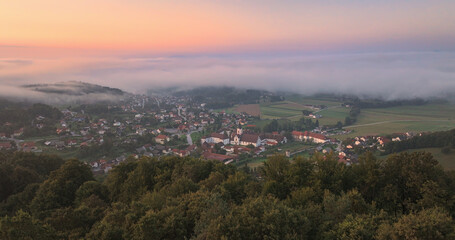 AERIAL: Village with historic monastery and rolling mists on a beautiful morning