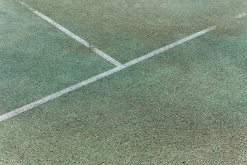 overhead view of the white lines marking a tennis court, revealing the textured surface of the court