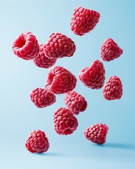 Fresh raspberries levitating in the air against a light blue background. Summer refreshment concept.	