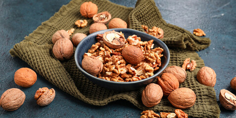 Bowl with tasty walnuts on black background
