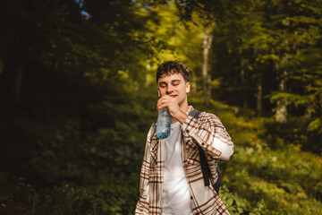 Adult young man walk around forest with backpack hold bottle of water