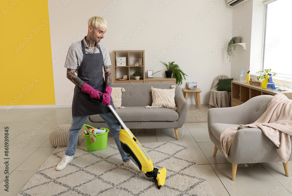 Poster young tattooed man hoovering carpet at home