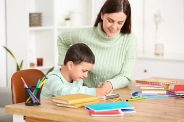 Cute little boy doing lessons with his mother at home