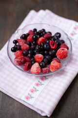 Frozen mixed fruits in a bowl - berries - strawberries, raspberries, black currants. A bowl with berries on a beautiful fabric