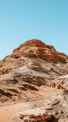 A scenic view of the Wadi Rum desert in Jordan, featuring a red rock formation with layered sandstone and a sandy valley in the foreground
