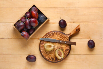 Box with fresh ripe plums on wooden background