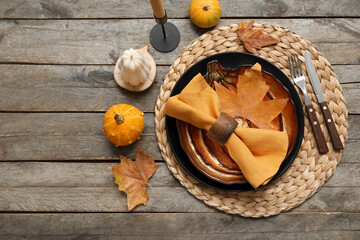 Autumn table serving with pumpkins, dry leaves and folded napkin on grey wooden table