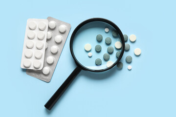 Magnifier with different pills on blue background