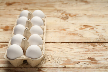 Chicken eggs in carton box on wooden background