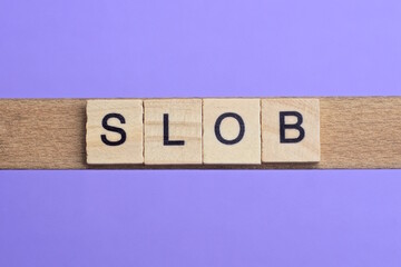 word slob made from wooden gray letters lies on a lilac background