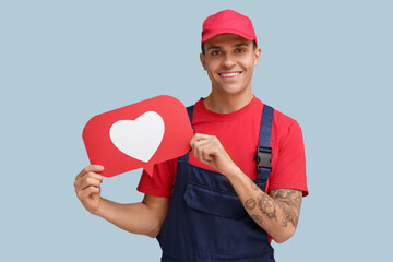 Handsome young happy male plumber with heart like icon on blue background