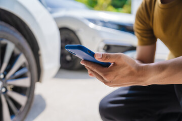 Man fills out a car insurance form after a car accident. Comprehensive motor insurance covers car damage. He files a claim report, speaking with an adjuster to understand his coverage and deductible.