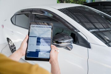 Man fills out a car insurance form after a car accident. Comprehensive motor insurance covers car damage. He files a claim report, speaking with an adjuster to understand his coverage and deductible.