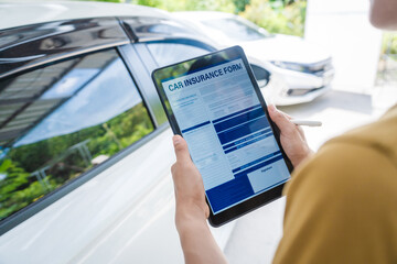 Man fills out a car insurance form after a car accident. Comprehensive motor insurance covers car damage. He files a claim report, speaking with an adjuster to understand his coverage and deductible.