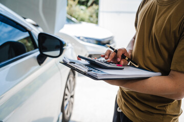 Man fills out a car insurance form after a car accident. Comprehensive motor insurance covers car damage. He files a claim report, speaking with an adjuster to understand his coverage and deductible.