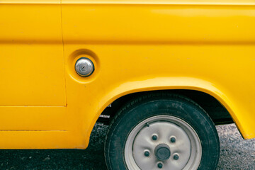 A yellow cars rear fender and wheel
