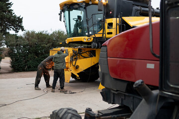 Hombres arreglando maquinaria agrícola, amoladora, reparación, campo, aire libre, zona rural