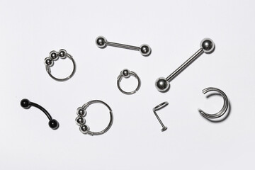 Composition with stylish jewelry for piercing on light background