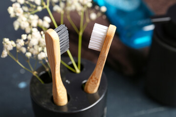 Cup with toothbrushes and gypsophila flowers on black grunge background