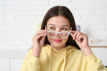 Beautiful young Asian woman with stylish eyeglasses at home