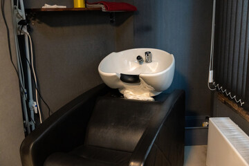 A white ceramic hair washing sink in a small salon room