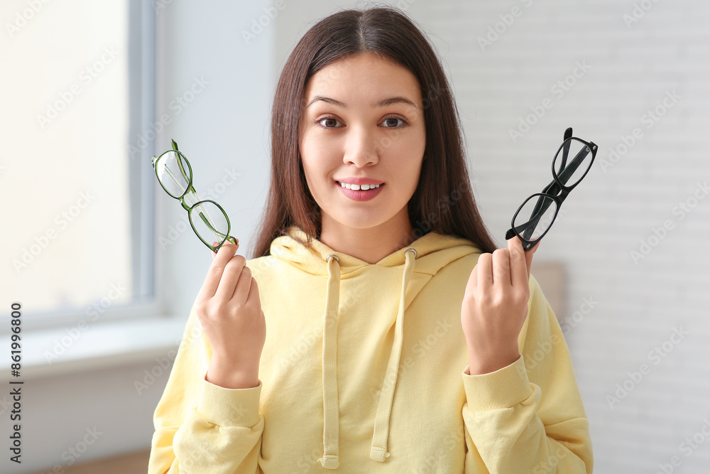 Wall mural Beautiful young happy Asian woman with stylish eyeglasses at home