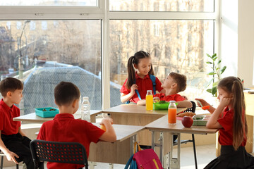 Cute little pupils having lunch in classroom