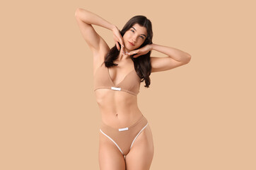 Pretty young woman in cotton underwear on beige background