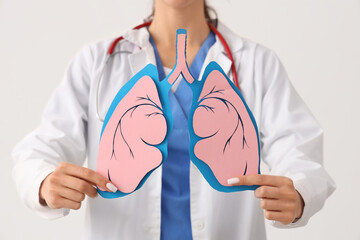 Female doctor with paper lungs on white background, closeup