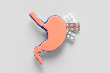 Paper stomach with pills on light background