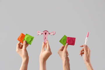 Women with paper uterus, condoms and pregnancy test on light background