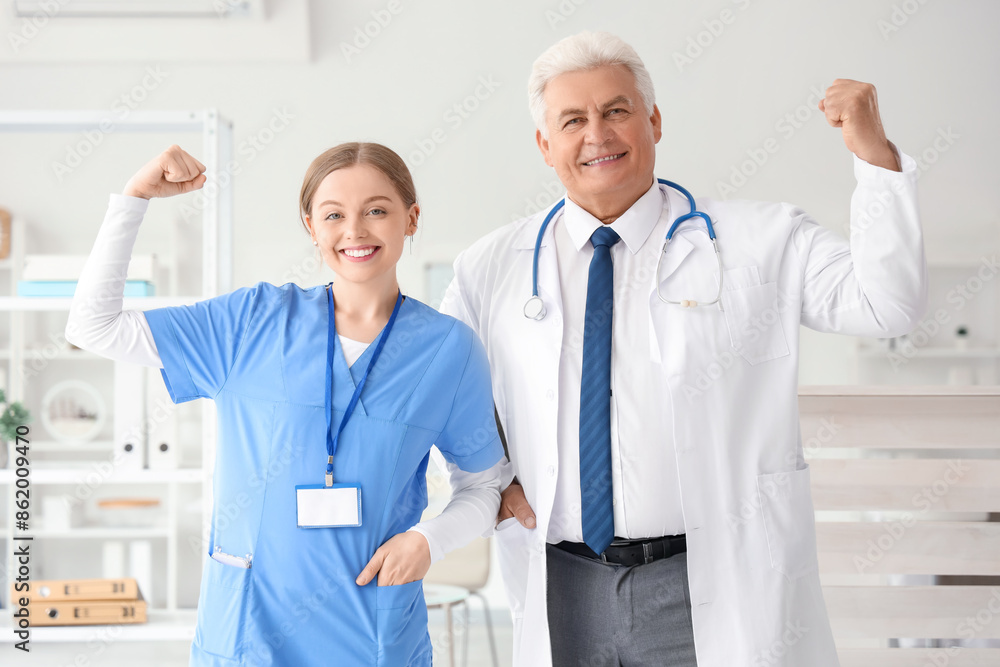 Wall mural Mature doctor with nurse showing muscles in clinic