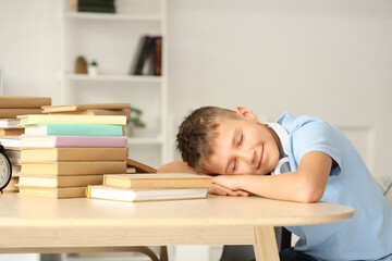 Teenage boy with books sleeping at table in library