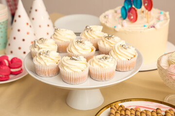 Dessert stand with tasty white cupcakes for birthday party on table
