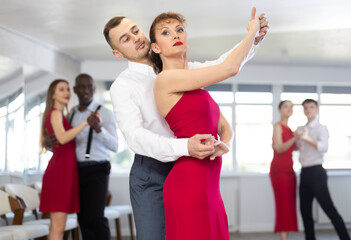 With unhurried music, guy and woman in couple spins to rhythm of waltz during lesson for novice students. Classes in mini-groups for those who want to learn dancing