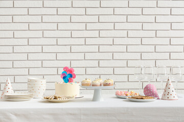Table with different sweets for birthday party against white brick wall