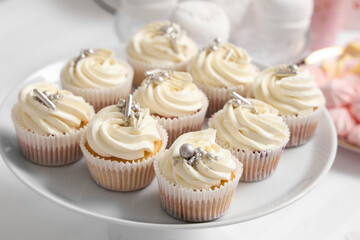 Dessert stand with tasty white cupcakes for birthday party on table, closeup