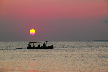 Beautiful sunrise on the sea and silhouette of a fishing boat